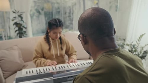 Girl Learning Piano from an Adult at Home