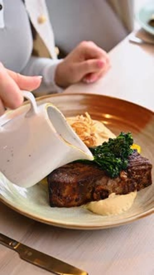 Pouring Delicious Gravy Over Tender Steak Dish Indoors