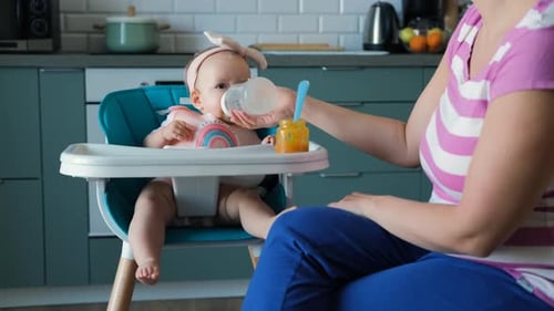 Cute Baby Being Fed in Highchair at Home