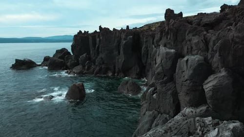 Top view of black rocks of sea coast on cloudy day