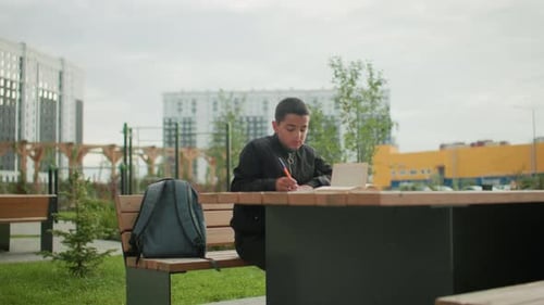 Focused Boy Studies at Table Outdoors