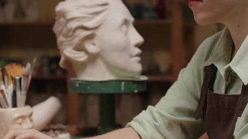 Female Sculptor Looking for Inspiration on Laptop in Workshop