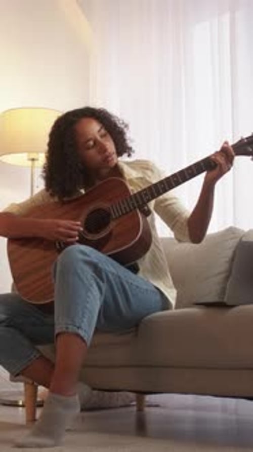 Woman Plays Guitar on Couch at Home