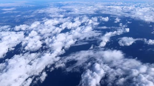 Weiße Wolken schweben über einem tiefblauen Meer, das von oben gesehen wird, und sorgen für eine friedliche Aussicht