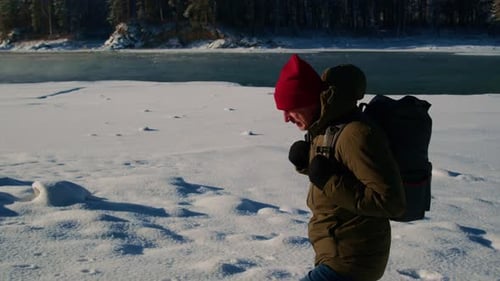 Man With Backpack Walking in Snowy Winter Landscape