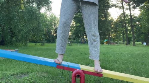 Barefoot Female Person Finds Equilibrium on Playground Outdoors