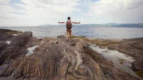 Man Embracing Coastal View with Arms Outstretched