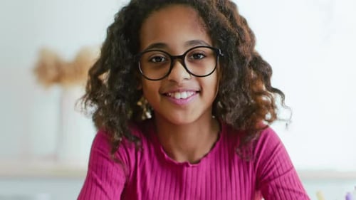 Smiling young girl with curly hair and glasses