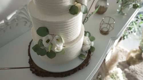 Elegant white wedding cake adorned with fresh flowers on a rustic wooden base