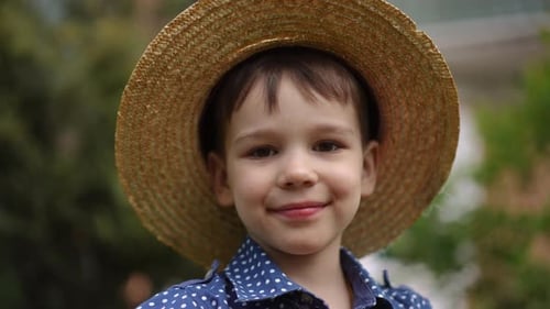 Smiling Boy with Straw Hat in a Garden