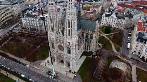 Drone aérien filmé en panoramique révélant la cathédrale votivkirche de Vienne avec des bâtiments en hiver
