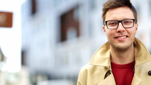Happy young man smiling outdoors wearing eyeglasses in the city