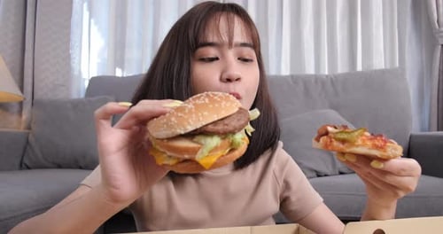 Close up asian woman takeaway eating junk food hamburger and pizza