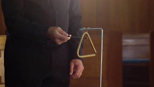 Percussionist playing triangle instrument wearing formal black suit