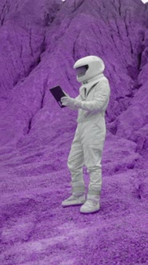 Vertical of Male Astronaut in White Suit and Helmet Working on Laptop