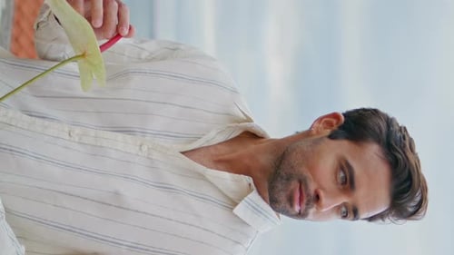 Young Man Holding an Anthurium Flower Indoors