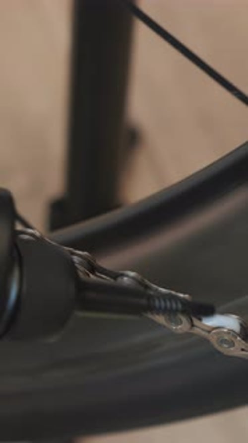 Bike mechanic lubricates bicycle chain with special lubricant. Vertical video