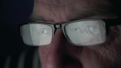 Man wearing glasses with financial data reflecting