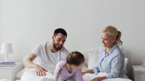 Family Jumping on Bed Having Fun Together Indoors
