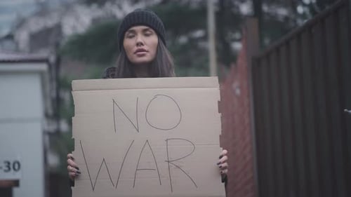 Die Frau hält ein Plakat aus Pappe mit der Aufschrift „Kein Krieg gegen die Ukraine“ in der Hand
