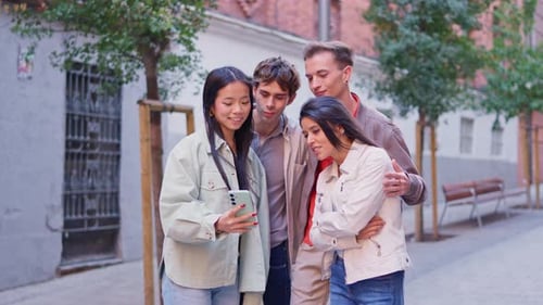 Young Adults Laughing at Phone on City Street