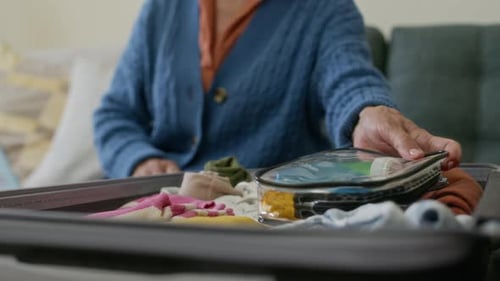Senior Woman Packing Travel Suitcase at Home