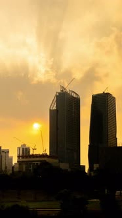 Sunset silhouette vertical time lapse video of tower cranes working on site project in a city.