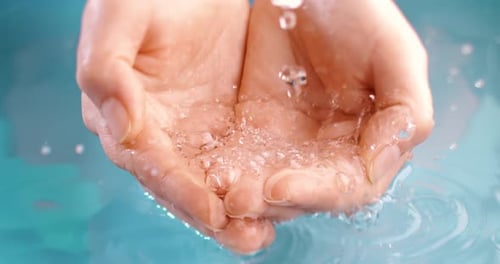 Clean drinking water flows in the palms of the woman hands. Shot on super slow motion camera 1000