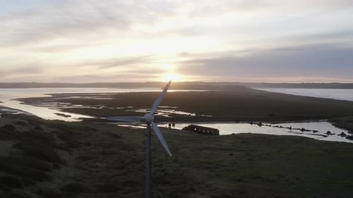 Sunrise aerial flies past wind turbine near Tramore Sandhills dunes
