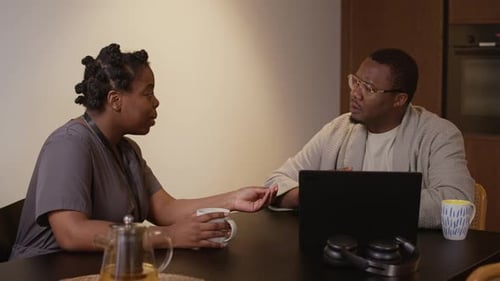 Couple Chatting at Table with Laptop and Coffee