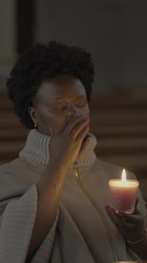 Woman Praying with Candle in Church Setting