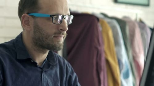 Man Working At Computer Answering Phone