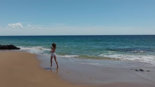Mädchen in Shorts läuft am Strand entlang