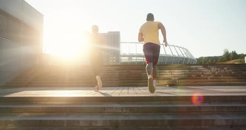 Athletic Pair Running Up Steps at Sunrise