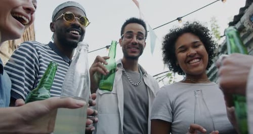 Slow Motion of Carefree People Students Clinking Bottles and Drinking Celebrating Holiday in Outdoor