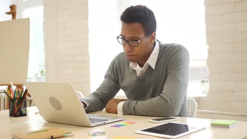 Young Man Working on Laptop in Bright Office