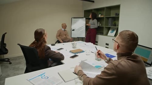 Female Office Manager Presenting at Board during Group Discussion at Meeting