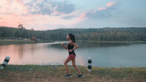 A young woman is running in nature outdoor at sunset
