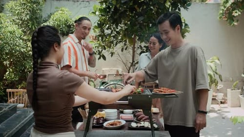 Friends Chatting while Cooking on Grill Outdoors