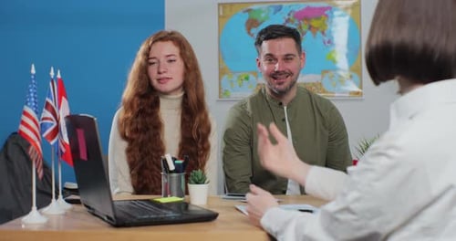 A Young Couple in a Travel Agency Choose a Country for a Summer Trip