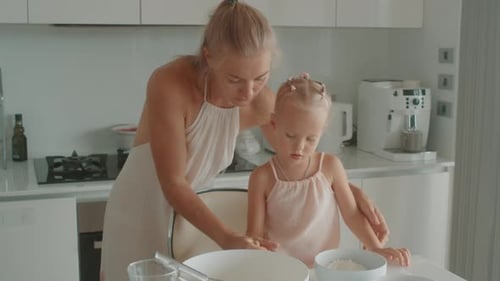 Loving Cheerful Mother and Little Daughter Having Fun While Cooking Pastries Sprinkling Sugar Powder