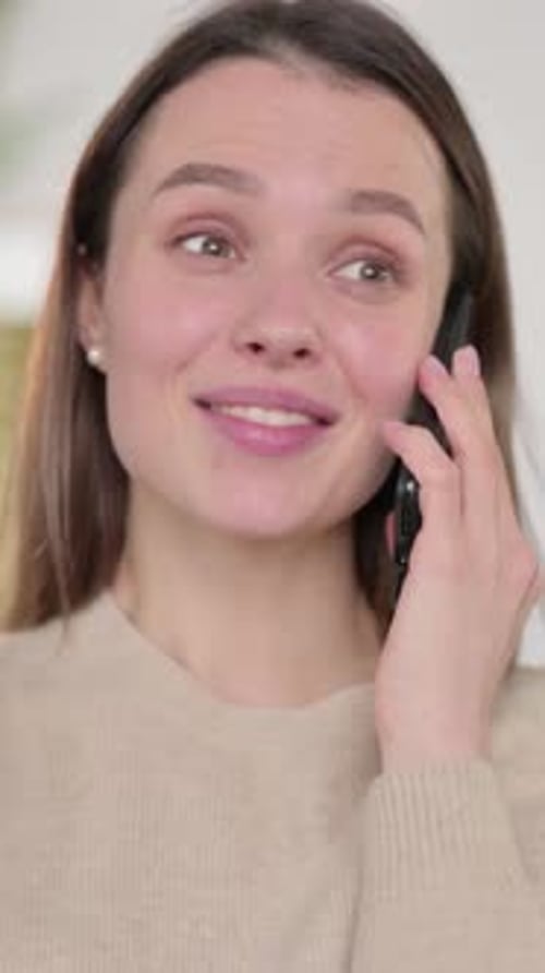 Cheerful Young Woman Talking on Smartphone Indoors