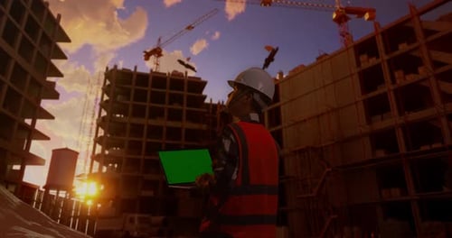Back View Of Asian Male Engineer Working On A Green Screen Laptop At Construction Site