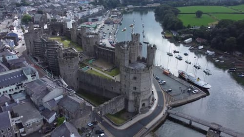 Ancient Caernarfon castle Welsh harbour town aerial view medieval waterfront landmark rising birdsey