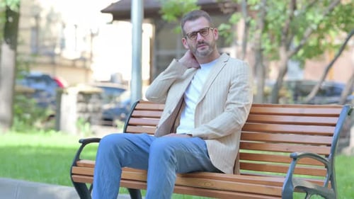 Man Massaging Neck While Sitting Outside
