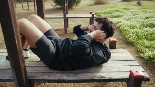 Man Trains on a Wooden Bench in the Outdoor Park
