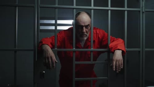 Man in Orange Jumpsuit Behind Prison Bars