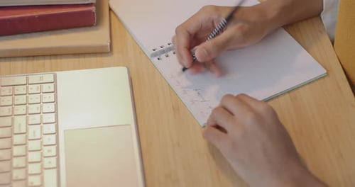 Closeup of Hand Writing in Notebook While Teenage Boy Studying Doing Homework at Table at Home