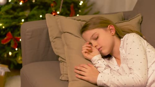 Girl Sleeping on Couch Christmas Tree in Background