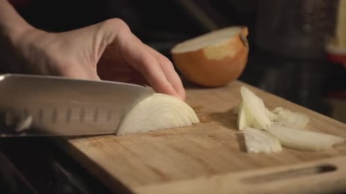 Chef's Hand Cutting Onion On A Wooden Board. - close up slow mo shot